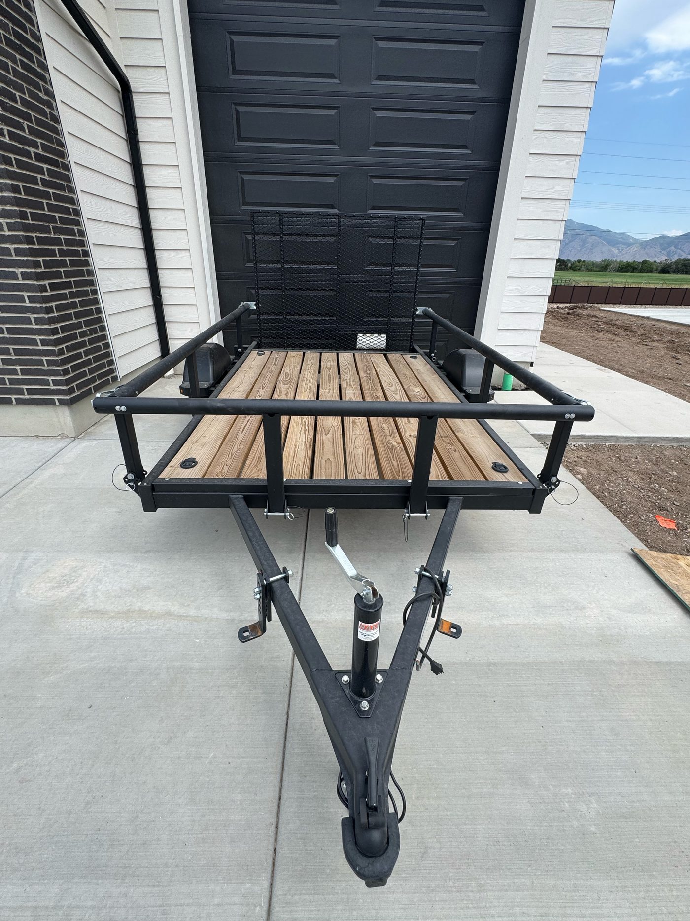Karavan 5.5x10 trailer from the front, showing the tongue, jack, wood deck and ramp gate